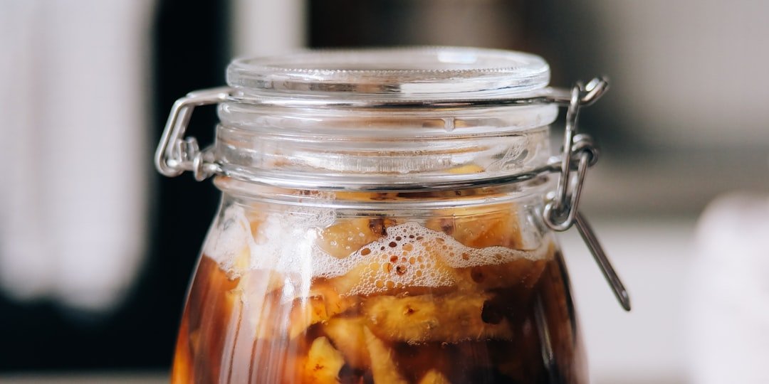 A clear glass jar containing brown liquid and floating ingredients