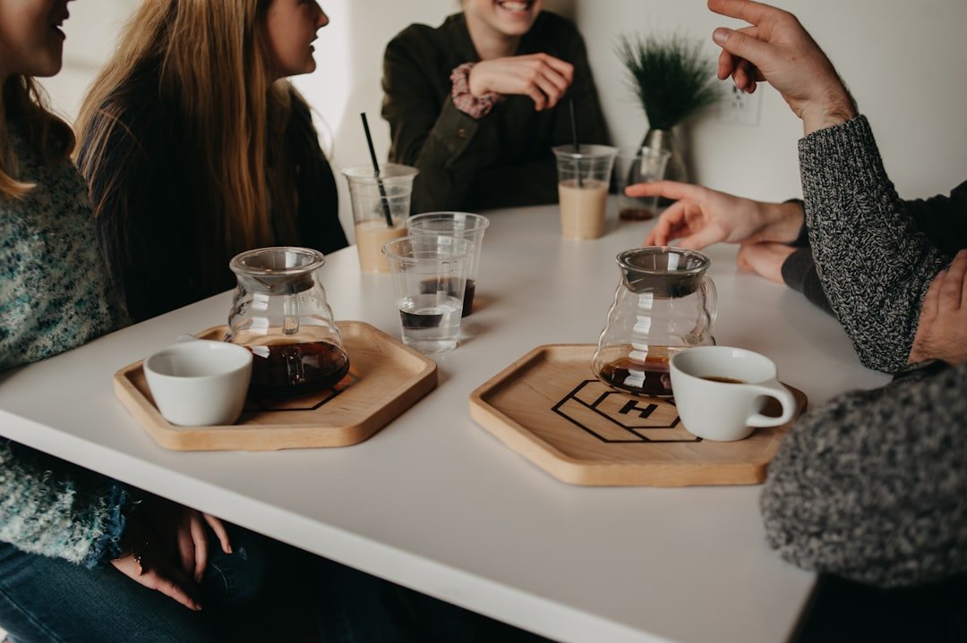 Friends gathered around coffee trays and cups at a shared table.