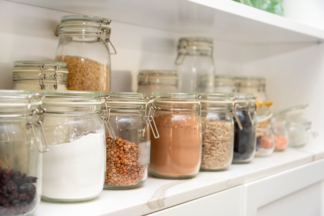 Glass pantry jars lined up on a bright shelf for small brewing supplies.