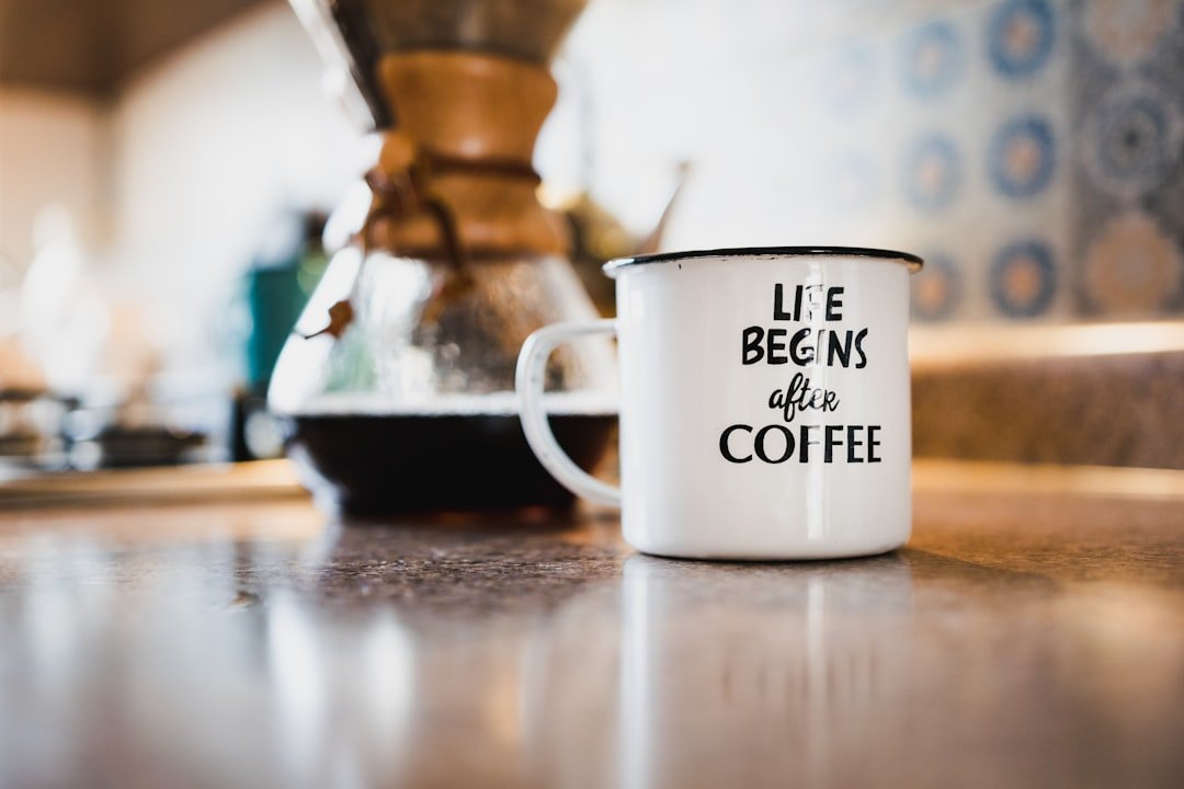 Enamel coffee mug and brewer on a warm kitchen counter.